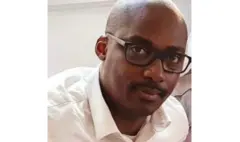 Léon Habyarimana yambaye indorerwamo n'ishati y'umweru. Arareba muri 'camera'.