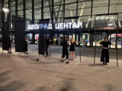 Nekoliko ljudi sa metalnim šipkama i tkaninom između izvode performans ispred Železničke stanice u Beogradu