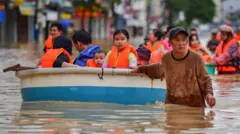 Мужчина ведет лодку с детьми по затопленной улице во Вьетнаме 20 ноября 2025 года
