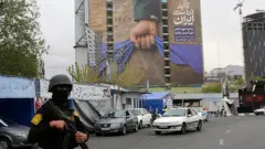 На снимке — большой рекламный щит, установленный на площади Ванак в Тегеране 12 апреля 2026 года. На щите размещены надписи о том, что Ормузский пролив останется под контролем Ирана и что Дональд Трамп не смог добиться результатов