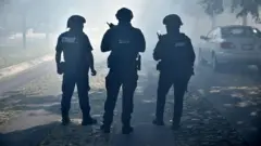 Tres policías, de espaldas en una calle