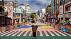 ሴዑል ከተማ እግረኛ መንገድ ላይ ምልክት የያዘች ሴት