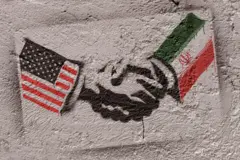 گرافیتی پرچم ایران و آمریکا روی دیوار که در حال دست دادن با هم هستند