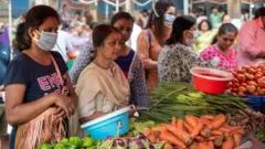 માસ્ક પહેરીને શાકભાજી ખરીદતાં મહિલા