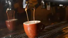 قهوة تنزل من ماكينة صنع قهوة في فنجان