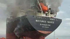 Esta foto, divulgada em 11 de março de 2026 e publicada pela Marinha Real Tailandesa, mostra fumaça saindo do navio graneleiro tailandês “Mayuree Naree” perto do Estreito de Ormuz após um ataque