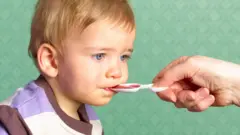 Маленький хлопчик приймає ліки з ложки - стокова фотографія