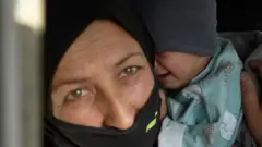 An Afghan woman holding a child