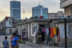Pessoas em seu dia a dia em um bairro de baixos recursos da capital de Cuba, Havana, com altos edifícios ao fundo