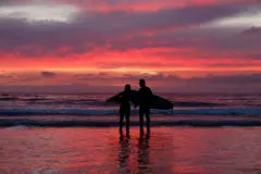 Dos surfistas miran un precioso atardecer rosado en las playas de LaJolla en California