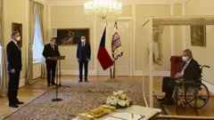 Czech President Milos Zeman, separated by a transparent wall after testing positive for the coronavirus , appoints Civic Democratic Party (ODS) leader Petr Fiala as the new prime minister.