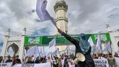Activists protest with white flags in front of a mosque in Banda Aceh to demand that the Indonesian government opens the door to foreign aid