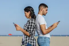 Um homem e uma mulher usando celulares