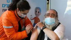 مسن إسرائيلي يأخذ جرعة من اللقاح ضد فيروس كورونا