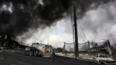 Обугленные машины и клубы дыма рядом с разбомбленным НПЗ "Шахран" в Тегеране