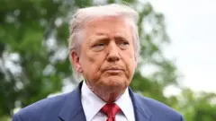 Donald Trump con una expresión seria, vistiendo un traje azul marino y una corbata roja.