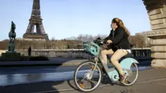 A cyclist wearing a protective mask rides a bike near the Eiffel Tower in Paris, France, 15 March 2021