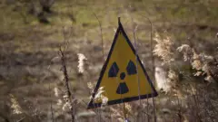 Sarı arka plan üzerine siyah renkli radyasyon uyarı levhası. 