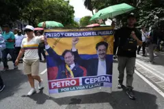 Una mujer y un hombre caminan sosteniendoo una pancarta con la imagen de Gustavo Petro e Iván Cepeda.