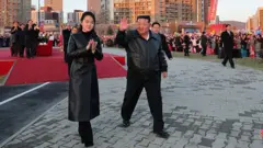 O líder norte-coreano, Kim Jong-un, e sua filha, Kim Ju-ae, acenam para cidadãos norte-coreanos