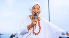 Queen Naomi speaking into a microphone