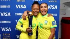 Marta e Ary Borges (que segura um troféu) abraçadas e sorrindo para foto