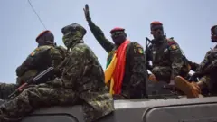 Guinea army special forces and coup leader Mamady Doumbouya wave hand ontop vehicle