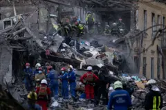 Equipes de resgate procuram pessoas sob os escombros de um prédio residencial destruído por um ataque com míssil russo em Kiev (Ucrânia)