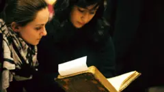 Estudiantes consultan un libro antiguo en la biblioteca de la Universidad Johns Hopkins