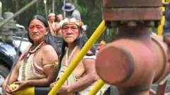 Dos mujeres indígenas miran hacia una conducción de petróleo en el Parque Nacional Yasuní.