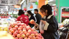 一名女士在超級巿場內挑選蘋果