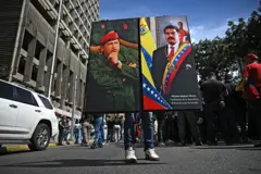 Chavista exibe um retrato de Chávez e outro de Maduro