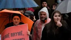 Protesters hold placards during a rally against electricity cuts in Pristina