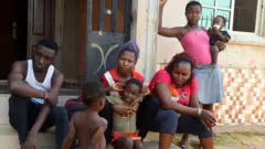 مهاجر عائد، يُدعى يونيتي (يساراً)، عاد إلى وطنه من ليبيا، يجلس مع أفراد عائلته في بنين، عاصمة ولاية إيدو في وسط غرب نيجيريا.