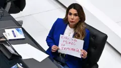 Marcela Villatoro segurando cartaz que diz 'hoje morreu a democracia'