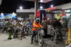 Dezenas de motociclistas formam fila em um posto de gasolina de Karachi, no Paquistão, na noite de 6 de março de 2026