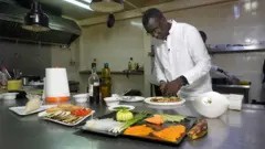 Tamsir Ndir dans sa cuisine en train de préparer un dessert