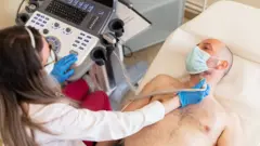 Homem deitado passa por exame de ultrassom da tireoide