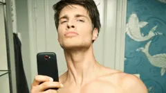 Homem jovem tirando uma foto no espelho