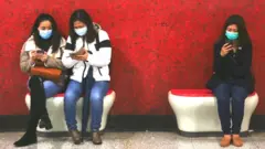 People wearing masks looking at phones