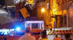 Вцілілий фунікулер на тлі пагорба, на якому видно рештки знищеного вагона. На передньому плані рятувальників і їхні автівки