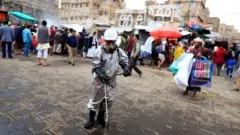 رجل يقوم بعملية تطهير ومن ورائه حشد من الناس