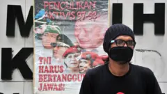 Seorang pengunjuk rasa duduk di samping spanduk bertuliskan "Penculikan aktivis 1997-1998, TNI harus bertanggung jawab".