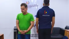 Silvinei Vasques com a cabeça baixa e as mãos cruzadas.