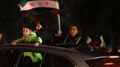 Arabanın camlarından dışarıya çıkmış üç çocuk var. Kız olan elinde Suriye bayrağı tutuyor.