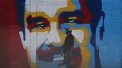 Mężczyzna przechodzi obok graffiti przedstawiającego prezydenta Wenezueli Nicolasa Maduro w Caracas, 3 stycznia 2026 r. Kolory użyte w graffiti to żółty, niebieski, czerwony i biały.