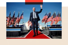 Stephen Miller llega a un mitin de campaña para el candidato presidencial republicano Donald Trump en el aeropuerto de Lancaster el 3 de noviembre de 2024 en Lititz, Pensilvania. Se lo ve caminando por una alfombra roja, con traje y saludando, con banderas estadounidenses a ambos lados.