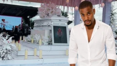 Image of Alexx beside im coffin wearing white