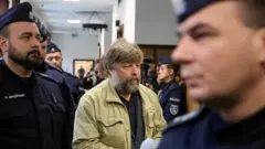 Мужчина с бородой в окружении полицейских