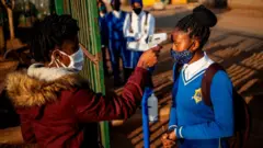 A pupil at Winnie Mandela School gets her temperature checked